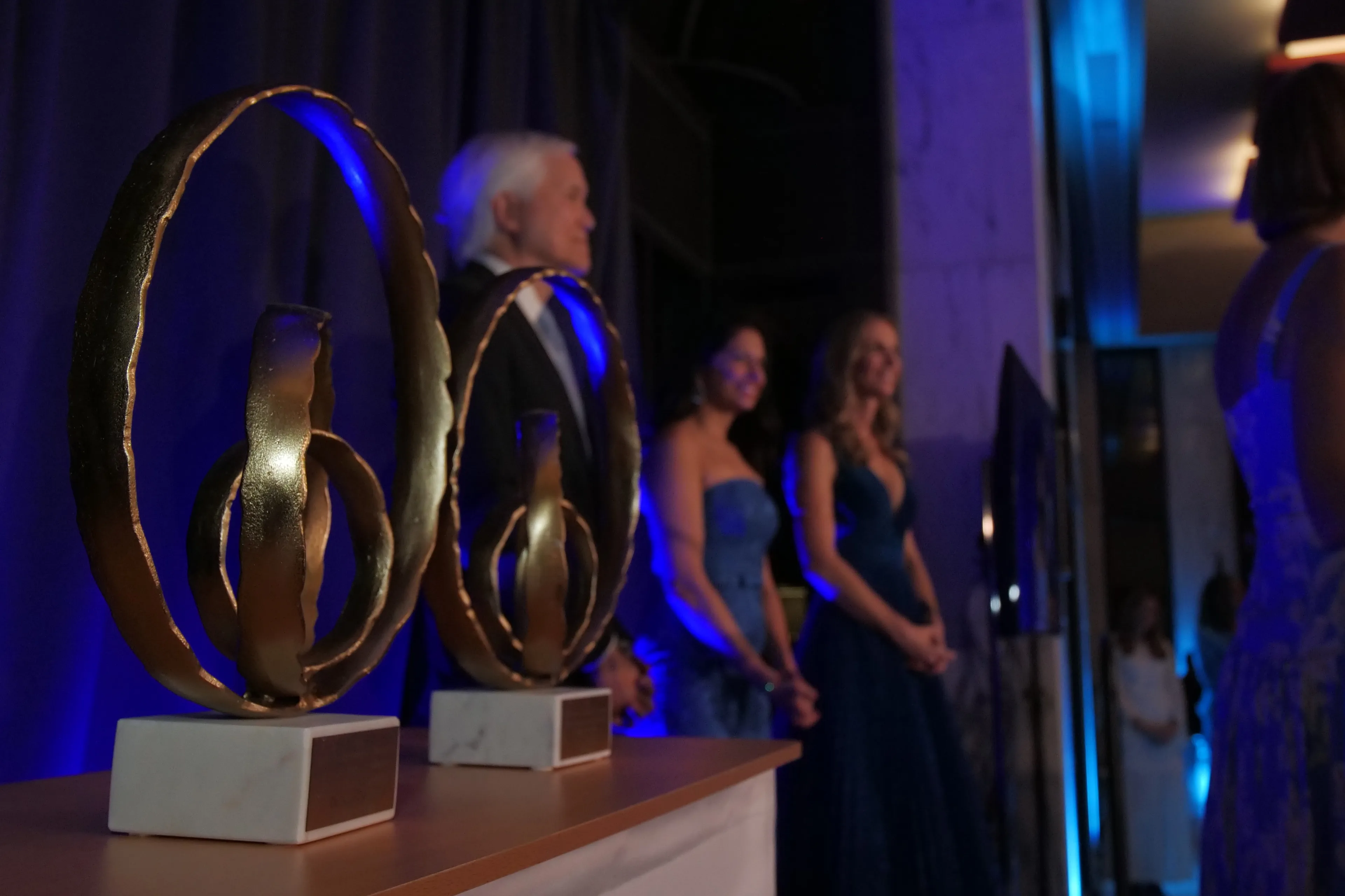 Awards displayed before a formal ceremony with guests gathered in the background.