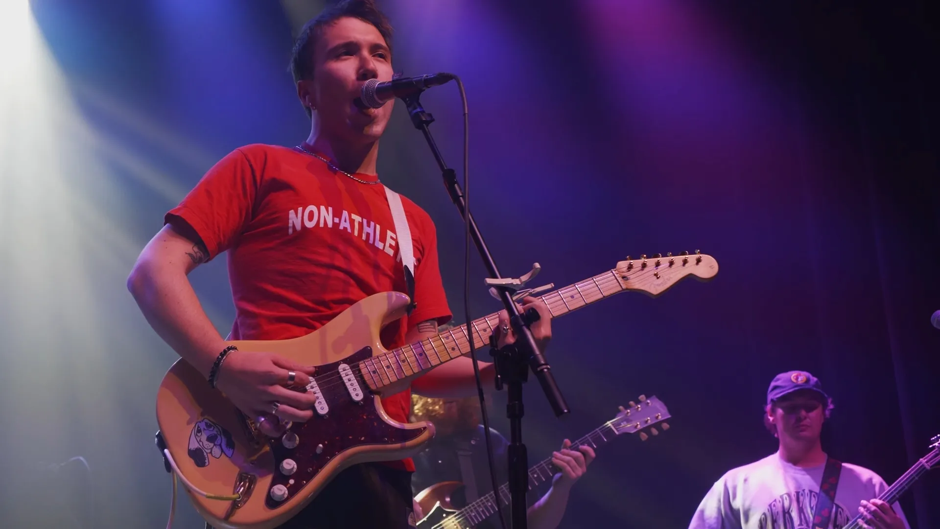 Guitarist singing with his band under stage lighting during a live music performance in Washington, DC.